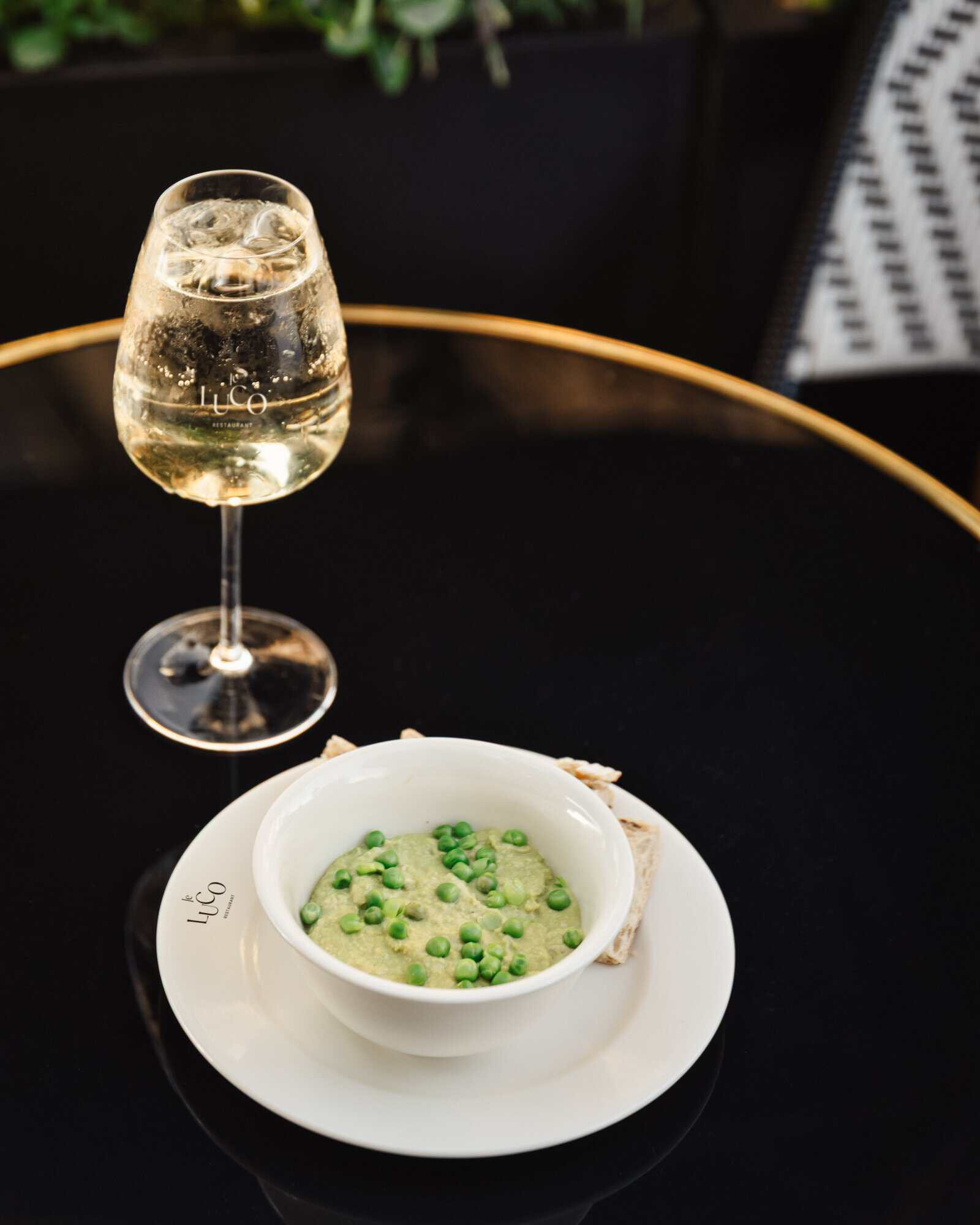 Glass of wine and a dish of pea purée at Le Luco restaurant in Paris